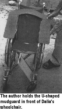 The author holds the U-shaped mudguard in front of Dalia's wheelchair.