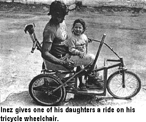 Inez gives one of his daughters a ride on his tricycle wheelchair.